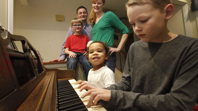 Megan and Kraig Neer of Dayton have been foster parents to several children, including their now-adopted daughter Mia, 2, who joined brothers Kaleb, 8, playing piano, and Blake, 5. CHRIS STEWART / STAFF