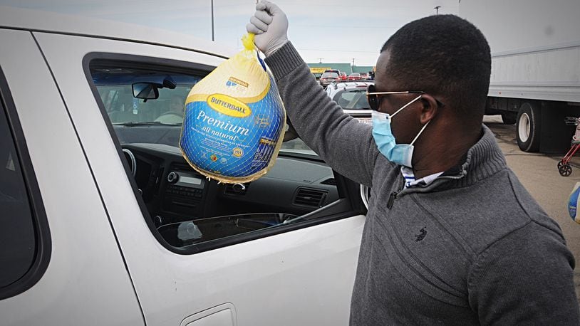 The old Kroger parking lot on Needmore Road looks like a car lot has people lineup to receive a free turkey from the God’s Grace Food Pantry Thursday. MARSHALL GORBY\STAFF