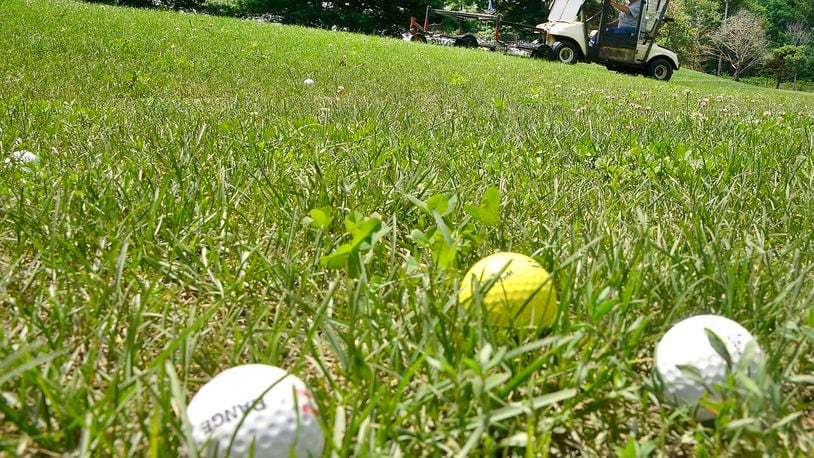 The tall grass makes it hard for a grounds keeper to pick up the balls on the driving range at Locust Hills Golf Course Thursday. Bill Lackey/Staff
