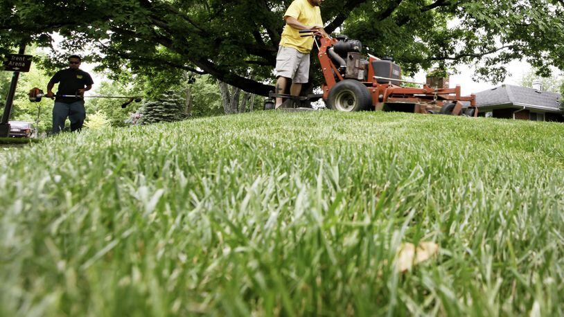 FILE PHOTO FROM 2013: Lawn care workers mow and trim a Kettering yard. CHRIS STEWART / STAFF