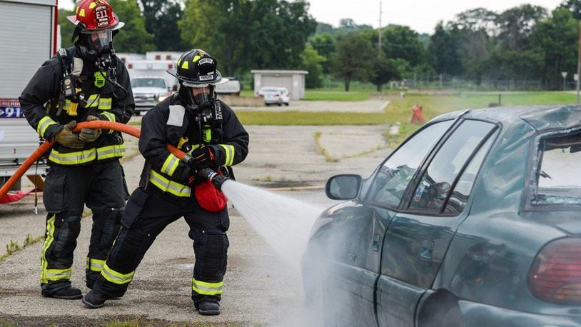 Firefighters from the 788th Civil Engineer Fire Department hose down a car that is supposed to be on fire on the scene of a simulated major crash during a base exercise at Wright-Patterson Air Force