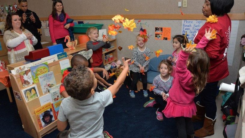 Angela Wilson, lead preschool teacher at New Horizons Child Development Center, and her class sing a fall jingle and toss leaves in celebration of the Harvest Luncheon, Nov. 20, 2015, Wright-Patterson Air Force Base. The CDC provided the event as an opportunity for parents to come and spend time with their children and enjoy a family-style lunch in the classrooms. (U.S. Air Force photo/Michelle Gigante)