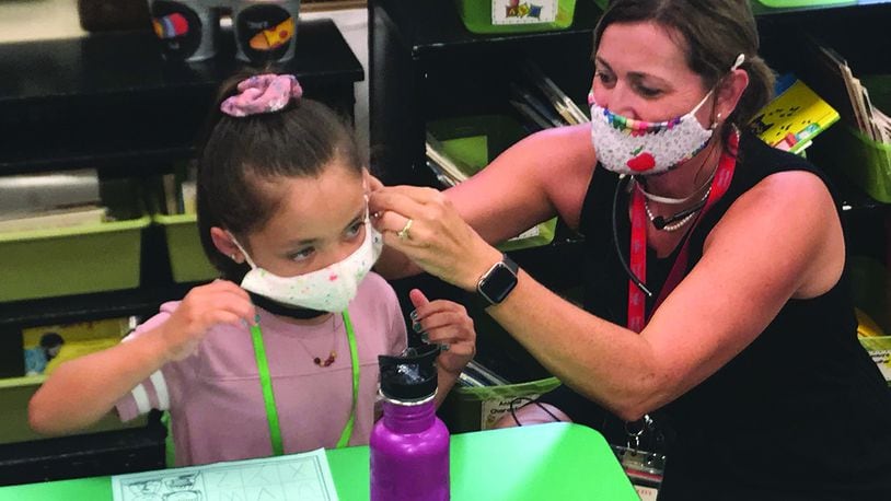 Heywood Elementary School first-grade teacher Angela Laird (right) helps student Madalyn Lee adjust her face mask on Troy City Schools' first day of school in fall 2020.