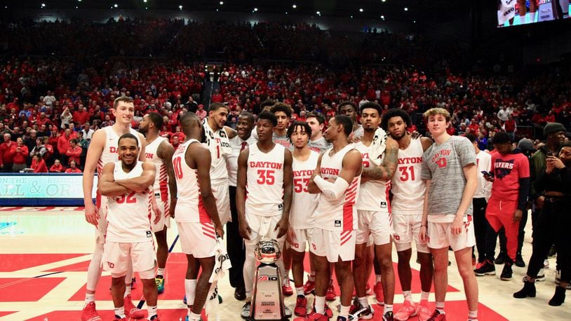 The Dayton Flyers pose with the Atlantic 10 Conference championship trophy after a victory against George Washington on March 7, 2020, at UD Arena. David Jablonski/Staff