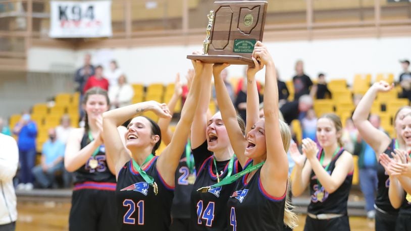 Tri-Village High School senior Torie Richards (left), Morgan Hunt (center) and Rylee Sagester (right) hoist the Division IV regional championship trophy after beating Fort Loramie on Saturday, March 4 at the Vandalia Butler Student Activity Center. CONTRIBUTED PHOTO BY MICHAEL COOPER