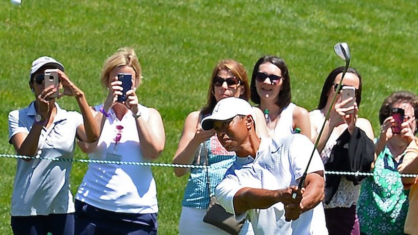 Fans take photos and watch as golfer Tiger Woods chips onto the 2nd green in preparation for the Wells Fargo Championship at Quail Hollow Club in Charlotte, N.C., on May 1, 2018. (Jeff Siner/Charlotte Observer/TNS)