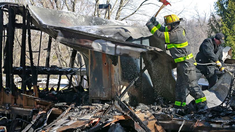 A firefighter from the Urbana Fire Division and the State Fire Marshall take apart the smoldering remains of a mobile home looking for a cause to last night’s fire that sent a family of four to the hospital. Bill Lackey/Staff