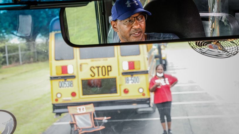 Dayton public schools bus driver in training, Barry Payne, in the mirror, learns to drive a school bus at the Welcome Stadium parking lot Tuesday August 9, 2022. JIM NOELKER/STAFF