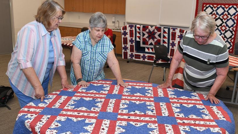 Volunteers in the Quilts of Valor program look at the 100th quilt made over five years locally as part of the military service recognition project. CONTRIBUTED