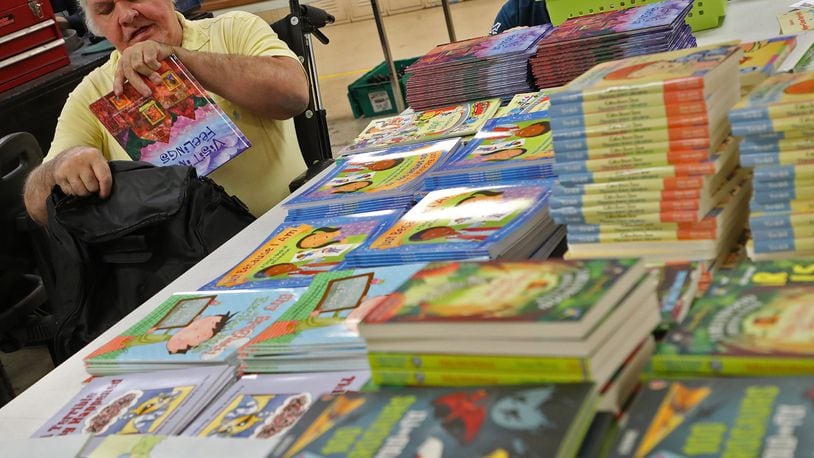 Jack Sharp, an employee at TAC Industries in Springfield, fills bags with childrens books for the Books to the Rescue program. TAC, which employs adults with disabilities, stocks Books to the Rescue bags with books and plush toys, then ships bags to participating agencies. BILL LACKEY/STAFF