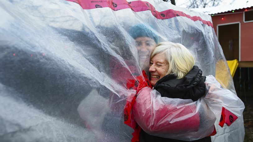 Carolyn Ellis, left, creator of the hug glove hugs her mother Susan Watts, 74, in her backyard on Christmas Eve during the COVID-19 pandemic in Guelph, Ont., Thursday, Dec. 24, 2020. Watts is a retired nurse who lives in an apartment near by and gets to come over outside and hug her daughter's family.  (Nathan Denette/The Canadian Press via AP)