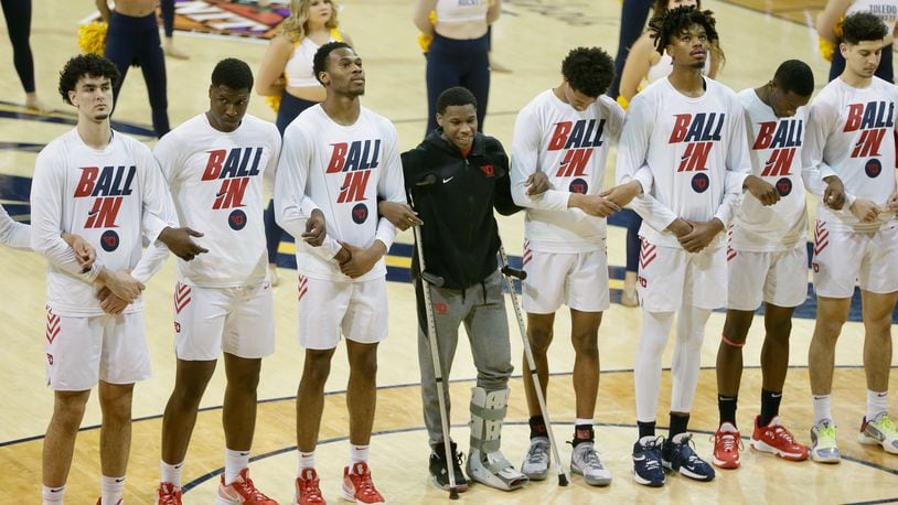 Dayton players, including Malachi Smith, center, stand for the national anthem before a game against Toledo in the first round of the NIT on Wednesday, March 16, 2022, at Savage Arena in Toledo. David Jablonski/Staff