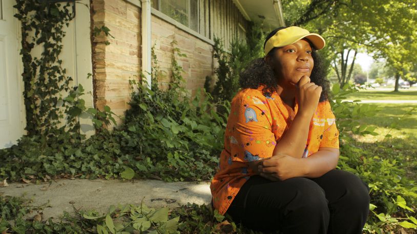 Erica Grissom sits on her front steps at 3691 Denlinger Road in Trotwood. Grissom's house was foreclosed on by a bank and she was forced to move. Years later, and $15,000 delinquent in property taxes, Grissom found out the house is still in her name. She is currently living in the house and working with Miami Valley Fair Housing to secure grants that will cover the back taxes and pay off the mortgage.