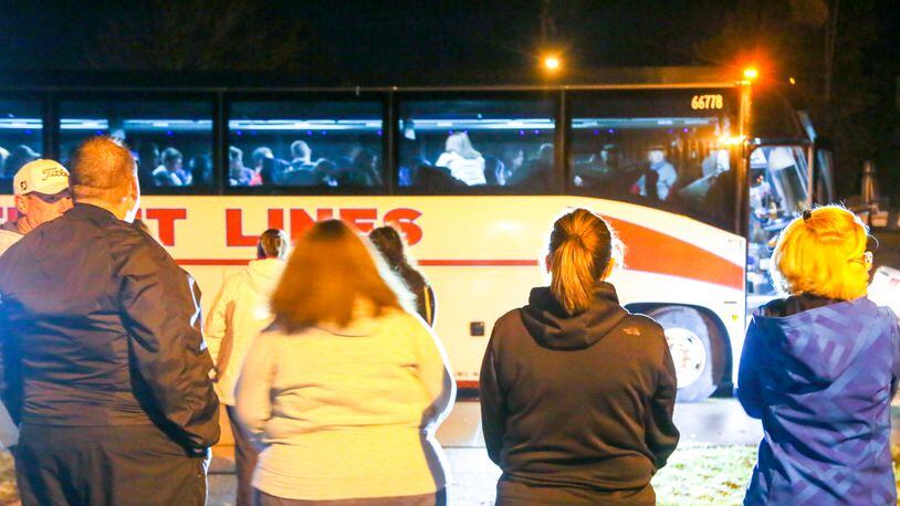 Parents watch as students from local schools board a charter bus heading to Washington, D.C., early Wednesday morning. The group is traveling to see President-Elect Donald Trump’s inauguration and other sites. GREG LYNCH / STAFF