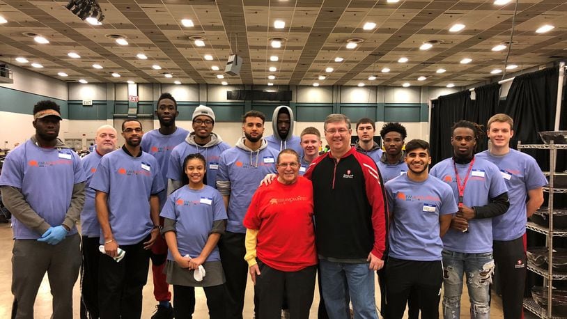 The Sinclair men’s basketball team gathers around Dr, Stephen Levitt, (red shirt ) co-chair of Feast of Giving celebration and Jeff Price (black jacket, red trim) head coach of Sinclair Tartan Pride. CONTRIBUTED PHOTO