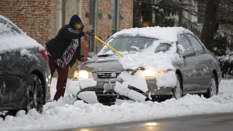 A Xenia resident clears heavy wet snow from her car on East Second Street on Wednesday morning after an overnight storm brought snow and freezing rain to the area. TY GREENLEES / STAFF