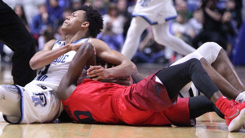 Rhode Island’s Jeff Downtin, left, and Dayton’s Jalen Crutcher compete for a loose ball on Friday, Feb. 23, 2018, at the Ryan Center in Kingston, R.I. David Jablonski/Staff