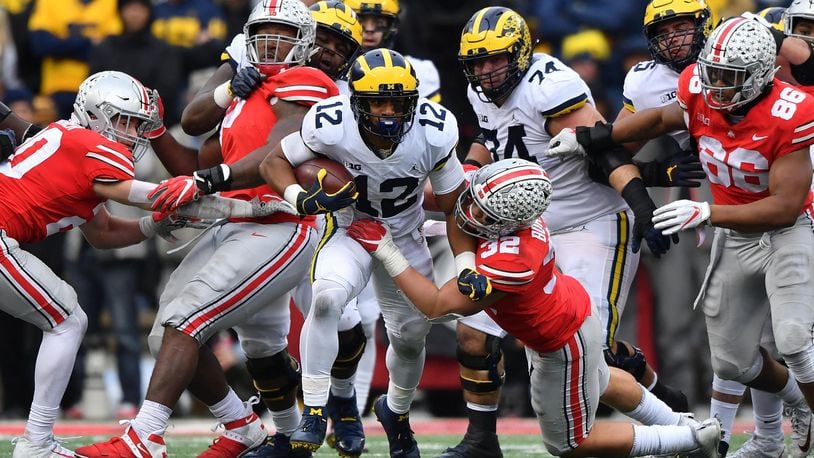 COLUMBUS, OH - NOVEMBER 24: Chris Evans #12 of the Michigan Wolverines breaks through the line as Tuf Borland #32 of the Ohio State Buckeyes drags him down in the fourth quarter at Ohio Stadium on November 24, 2018 in Columbus, Ohio. Ohio State defeated Michigan 62-39. (Photo by Jamie Sabau/Getty Images)