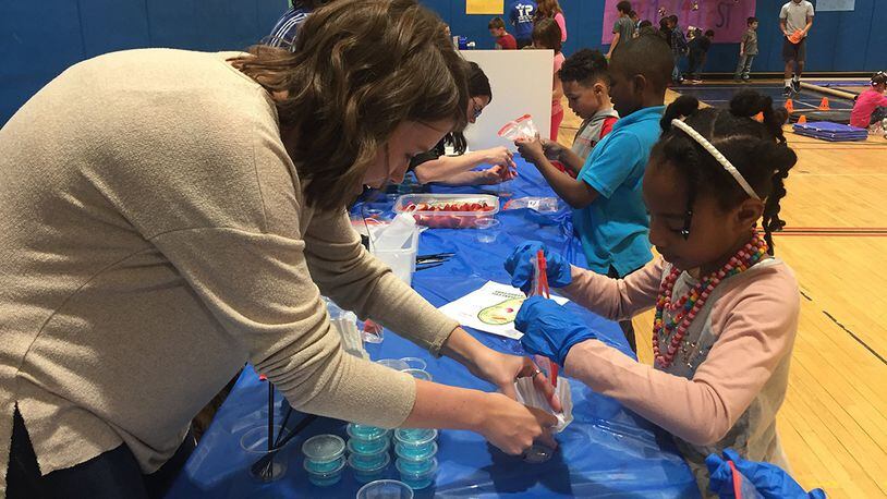 Christina Davis, student research assistant with the 711th Human Performance Wing, Air Force Research Laboratory, assists a student with identifying plant cell structures by extracting visible DNA from crushed and strained strawberries during STEMfest 3.14 at the Youth Center, Wright-Patterson Air Force Base, March 14. (Skywrighter photo/Amy Rollins)