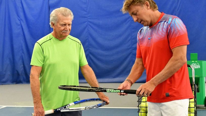 Bud Schroeder (right) talks tennis with a player at his Tipp City tennis center. CONTRIBUTED