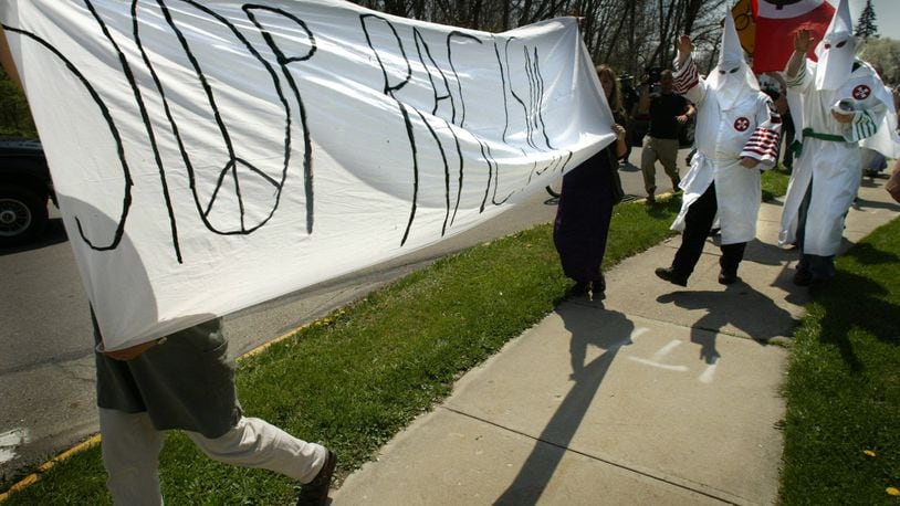 Hooded and robed members of the Ku Klux Klan walk down a sidewalk in Yellow Springs to protest racial discrimination against whites in 2004. Protesters to their appearance, meanwhile, carry a “stop racism” sign. The event was without arrests. STAFF/FILE