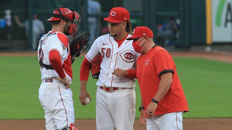 Reds catcher Curt Casali, pitcher Luis Castillo and pitching coach Derek Johnson talk during a game against the Royals on Tuesday, Aug. 11, 2020, at Great American Ball Park in Cincinnati. David Jablonski/Staff