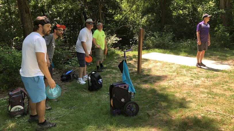 Sam Hartleroad, Garrett Heise, Brian Foster and J.P. Elam (from right) admire Russ Foster’s tee shot from the 3rd hole of the disc golf course at Armco Park in Warren County. STAFF/LAWRENCE BUDD