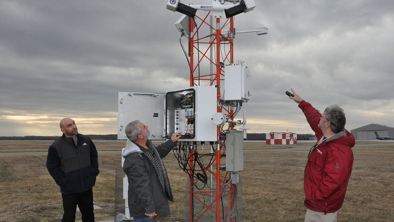 Meteorologist Scott Lutz (from left), Electronics Technician Marvin Mullins and Forecaster Brent Sullins, all personnel in the 88th Operations Support Squadron who keep the weather station at Wright-Patterson Air Force Base up and running, discuss the capabilities of the FMQ19, an automated weather observing system located on the base flight line. (U.S. Air Force photo/Gina Marie Giardina)