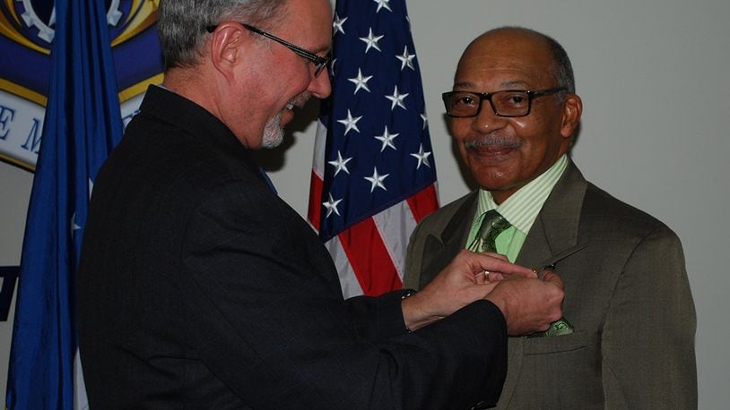 Thomas Doyon, director of the Air Force Materiel Command Law Office at Wright-Patterson Air Force Base, awards Fred Bennett Sr., a patent illustrator, with a gold pin commemorating 50 years of federal service Dec. 12 in Bldg. 11, Area B. (U.S. Air Force photo/Fred Rojas)