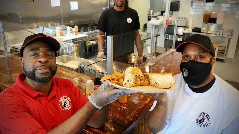 Co-Owners DeShawn Davis, on the left, and Walter Jones, on the right, pose with chief Denyan Blackmon with a King Burrito he made at the new Crazy King Burrito, located at 2624 Colonel Glenn Highway. MARSHALL GORBY\STAFF