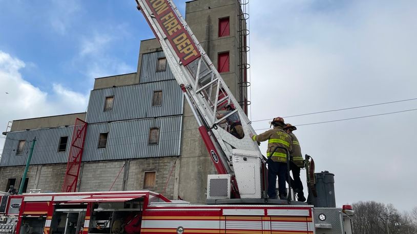 A participant is assisted by Dayton Fire Dept. personnel as she ascends the 137-foot aerial ladder during Saturday's Fire Camp for Women event. AIMEE HANCOCK/STAFF