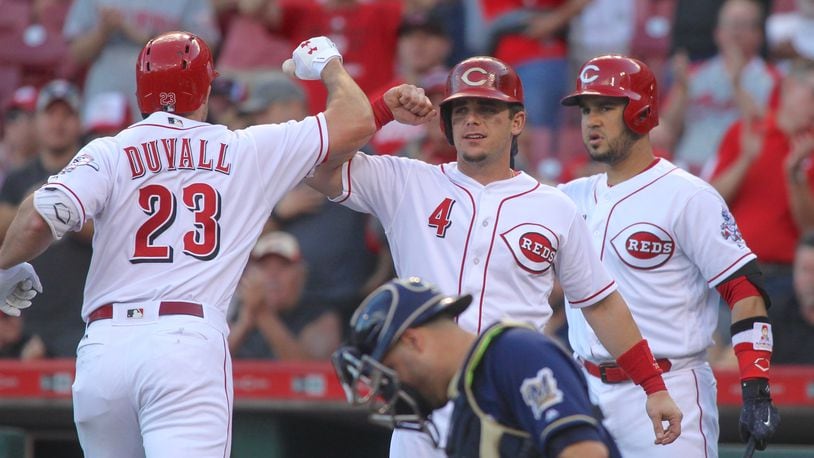 The Reds’ Adam Duvall, left, celebrates a home run with Scooter Gennett, center, and Eugenio Suarez in teh first inning against the Brewers on Tuesday, June 27, 2017, at Great American Ball Park in Cincinnati. David Jablonski/Staff