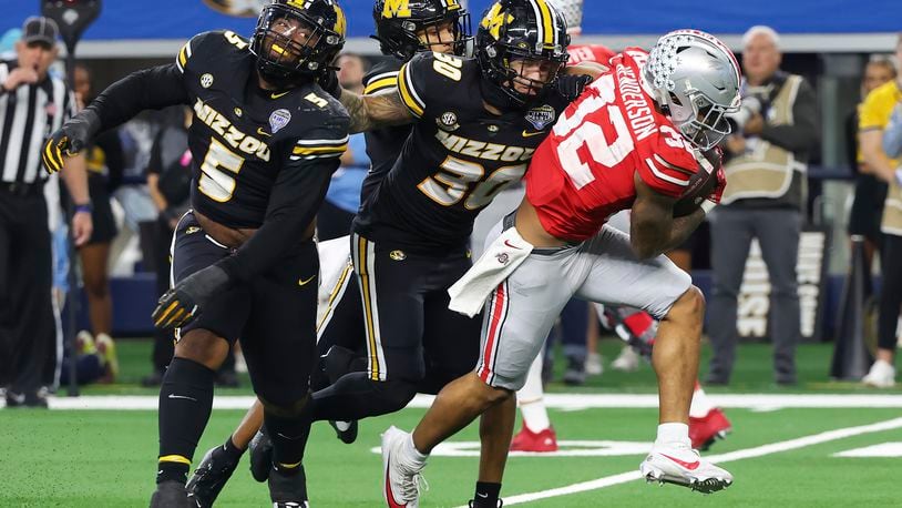 Ohio State running back TreVeyon Henderson (32) tries to get away from Missouri defensive lineman Kristian Williams (5) and linebacker Chuck Hicks (30) during the second half of the Cotton Bowl NCAA college football game Friday, Dec. 29, 2023, in Arlington, Texas. (AP Photo/Richard W. Rodriguez)