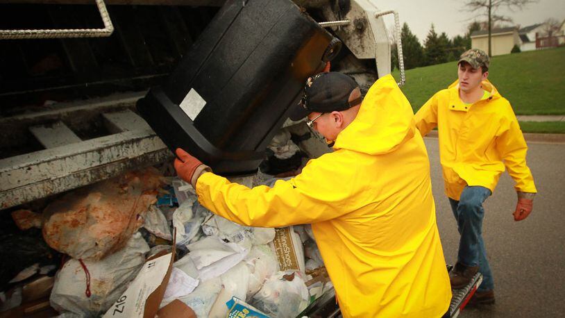 Waste management employees remove residential trash. FILE