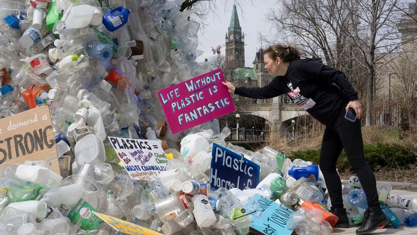 FILE - Activist Dianne Peterson places a sign on an art installation outside a United Nations conference on plastics, April 23, 2024, in Ottawa, Ontario. (Adrian Wyld/The Canadian Press via AP. File)