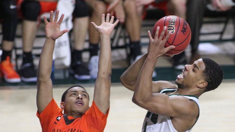 Ohio’s Jaaron Simmons shoots over Bowling Green and Wayne grad Rodrick Caldwell in a February game at the Convocation Center in Athens. David Jablonski/Staff