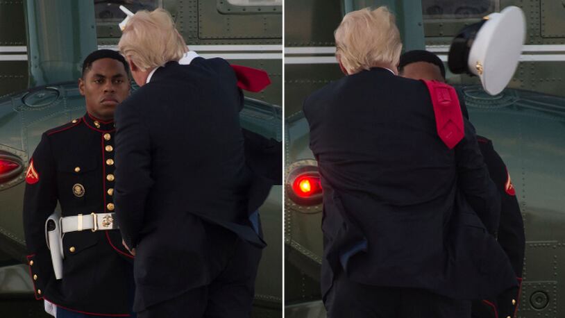 US President Donald Trump tries to catch a hat that the wind had blown from the head of a US Marine guarding Marine One following Trump's arrival at Andrews Air Force Base in Maryland, July 8, 2017, following a 4-day trip to Poland and Germany for the G20 Summit. (SAUL LOEB/AFP/Getty Images)