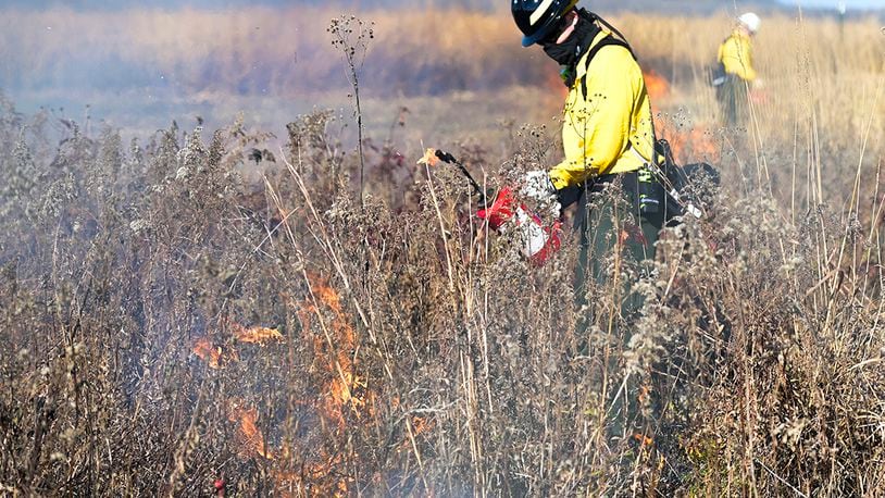 A firefighter with the U.S. Air Force Wildland Fire Branch Wildland Support Module uses a drip torch to set fire to parts of Huffman Prairie as part of the annual prescribed burn Nov. 12. U.S. AIR FORCE PHOTO/WESLEY FARNSWORTH