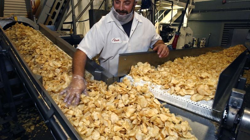 Chuck Marcum spreads fresh potato chips on the coveyor belt in the kettle room of Mikesell’s. TY GREENLEES / STAFF