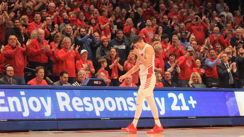 UD Arena public address announcer Jeff Stevens, front row, second from left, watches as Dayton's Ryan Mikesell leaves the court for the final time as a Flyer on March 7, 2020, in the final minutes of a victory against George Washington. David Jablonski/Staff
