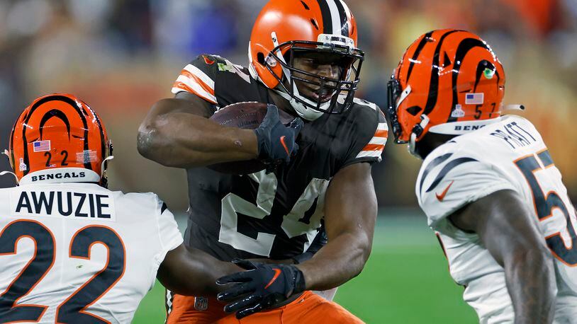Cleveland Browns running back Nick Chubb (24) carries the ball with Cincinnati Bengals cornerback Chidobe Awuzie (22) and linebacker Germaine Pratt (57) defending during the first half of an NFL football game in Cleveland, Monday, Oct. 31, 2022. (AP Photo/Ron Schwane)
