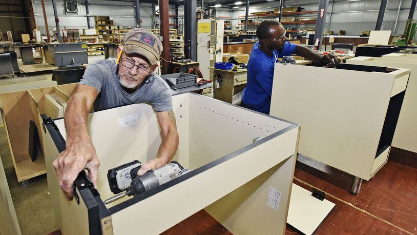 Jesse Combs, left, and Devinn Parms build cabinets at Custom Millcraft Corporation Tuesday, Oct. 10 in West Chester Twp. The fixture manufacturer specializes in high-end fixture work and complete millwork packages for retail, restaurant, banking and healthcare industries. The company is expanding its workforce. NICK GRAHAM/STAFF