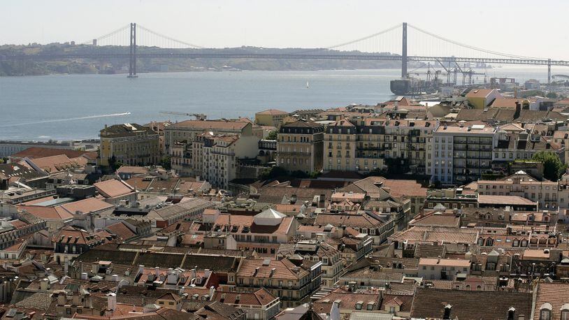 The rooftops of city apartments sit beside the Tagus river near the 25th April Tagus Bridge in Lisbon, Portgual, onJuly 25, 2015. Bloomberg photo by Pau Barrena.
