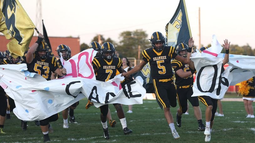 Shawnee’s Robie Glass leads the Braves onto the field before their game against Tecumseh. BILL LACKEY/STAFF
