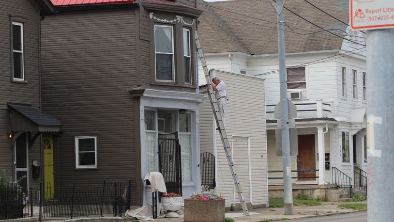 A man works on the exterior of a home in East Dayton earlier this year. CORNELIUS FROLIK / STAFF