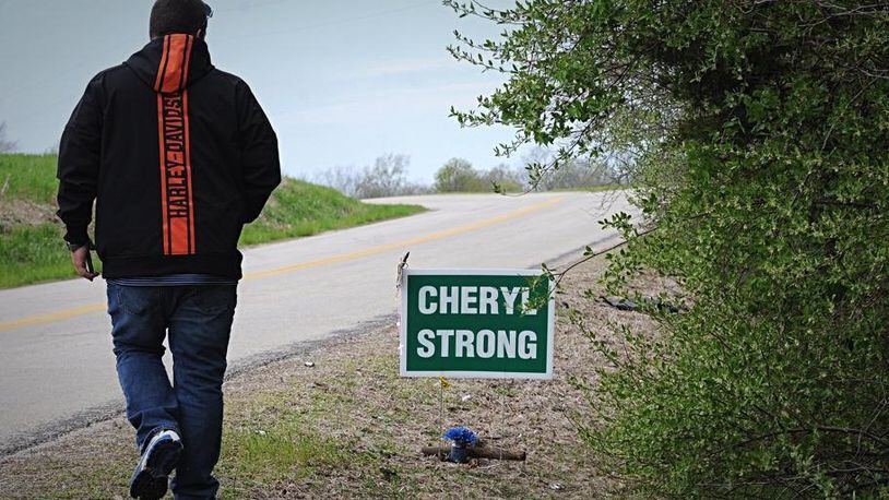 A friend of Cheryl Coker’s is shown next to a sign that was placed near where her remains were found over the weekend in Greene County. MARSHALL GORBY / STAFF