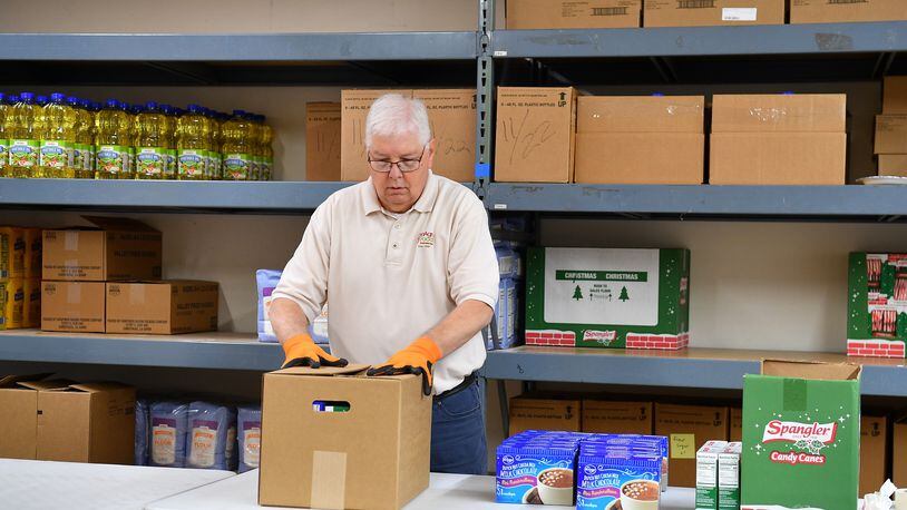 Volunteer Dan McMullen works on packing food boxes for distribution during this year's Needy Basket holiday program. The program based in Tipp City has been helping families at Christmas for more than 75 years. Contributed photo