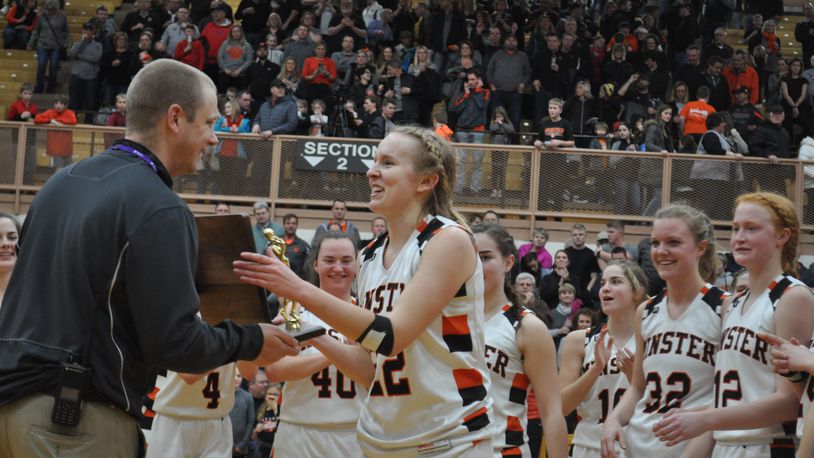 Minster senior forward Jessica Falk (right) accepts the Division IV regional championship trophy on behalf of her team from Butler athletic director Jordan Shumaker following the Wildcats’ win against Fort Loramie in the final, March 9, 2019. Nick Dudukovich/CONTRIBUTED
