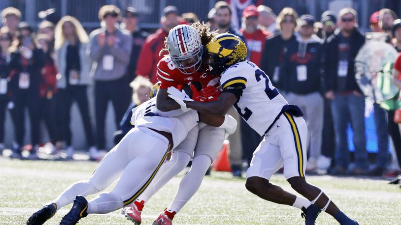Michigan defensive back R.J. Moten, left, and defensive back Gemon Green tackle Ohio State tight end Gee Scott during the first half of an NCAA college football game on Saturday, Nov. 26, 2022, in Columbus, Ohio. (AP Photo/Jay LaPrete)