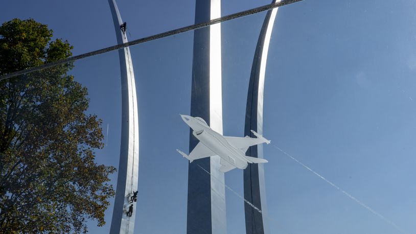 Tim Ball, Kevin Wilkinson, and John Gonzales climb Air Force Memorial for a routine inspection on Wednesday, Nov. 10, 2021, in Arlington, Va., as seen through an etched glass panel.  (AP Photo/Gemunu Amarasinghe)